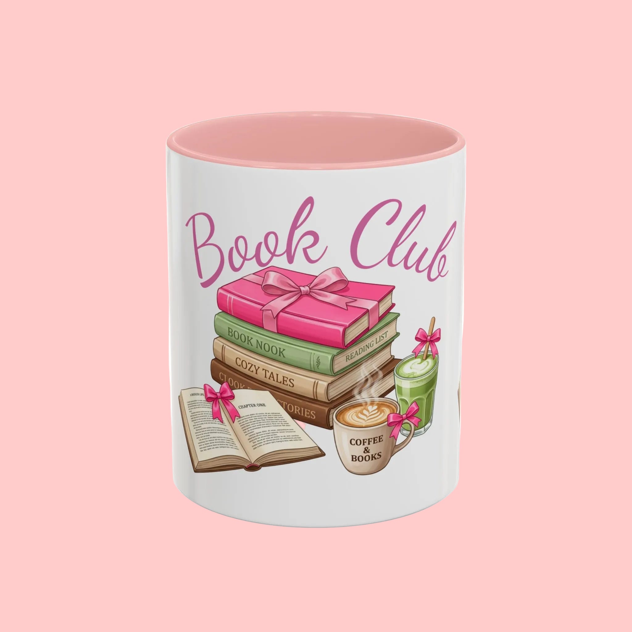 A white ceramic mug with a pink interior, featuring a 'Book Club' graphic with a stack of colorful books, an open book, a coffee cup, and a green jar tied with pink ribbons.