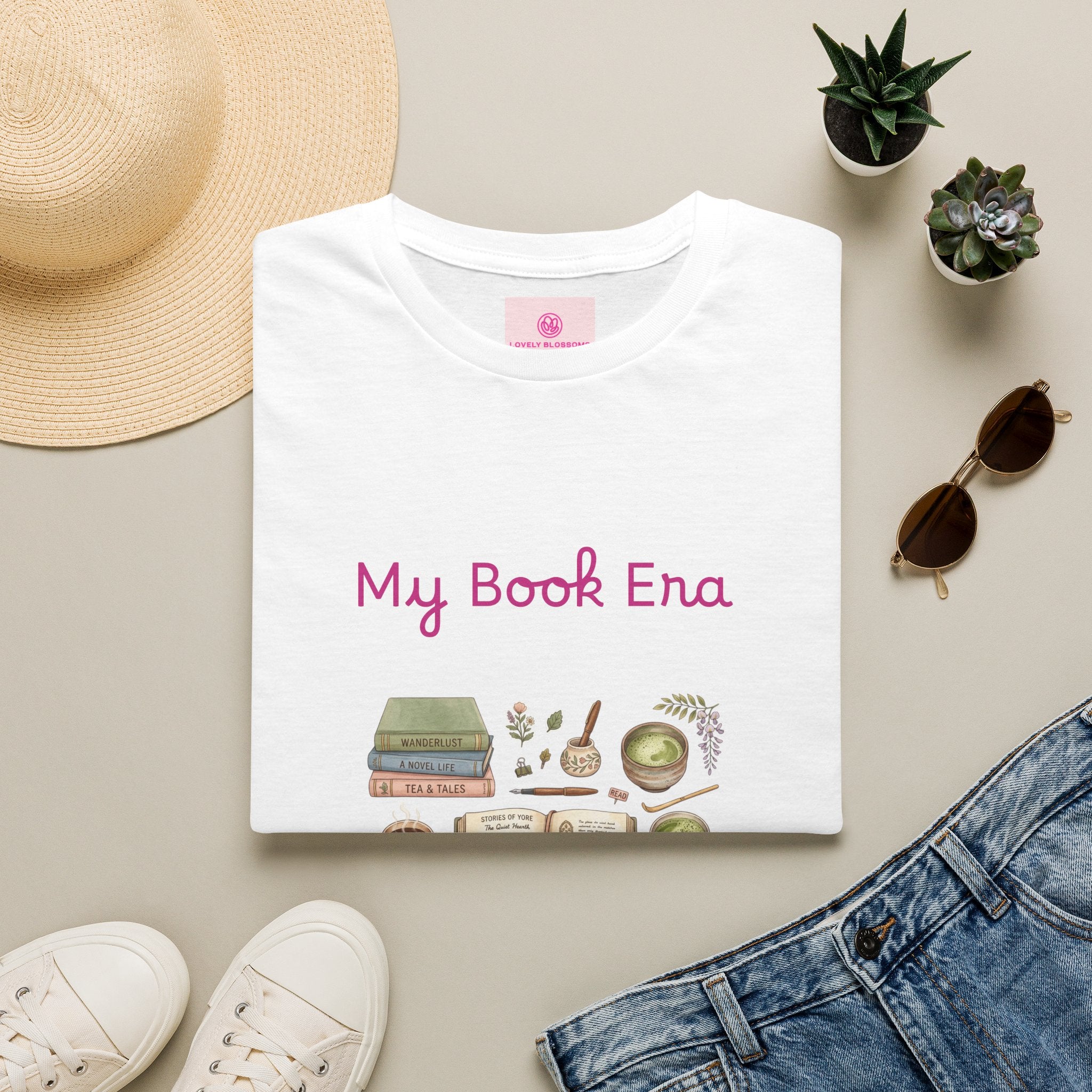 White t-shirt with blue stars and 'My Book Era' printed on it, surrounded by books, coffee, matcha, and plants.
