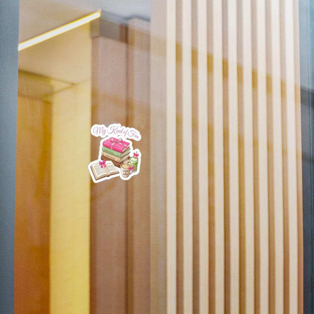 A small die-cut sticker with the text 'My Books' and an illustration of a pink frosted cake, an open book, and a small cup, shown applied to a glass door in a modern interior setting.