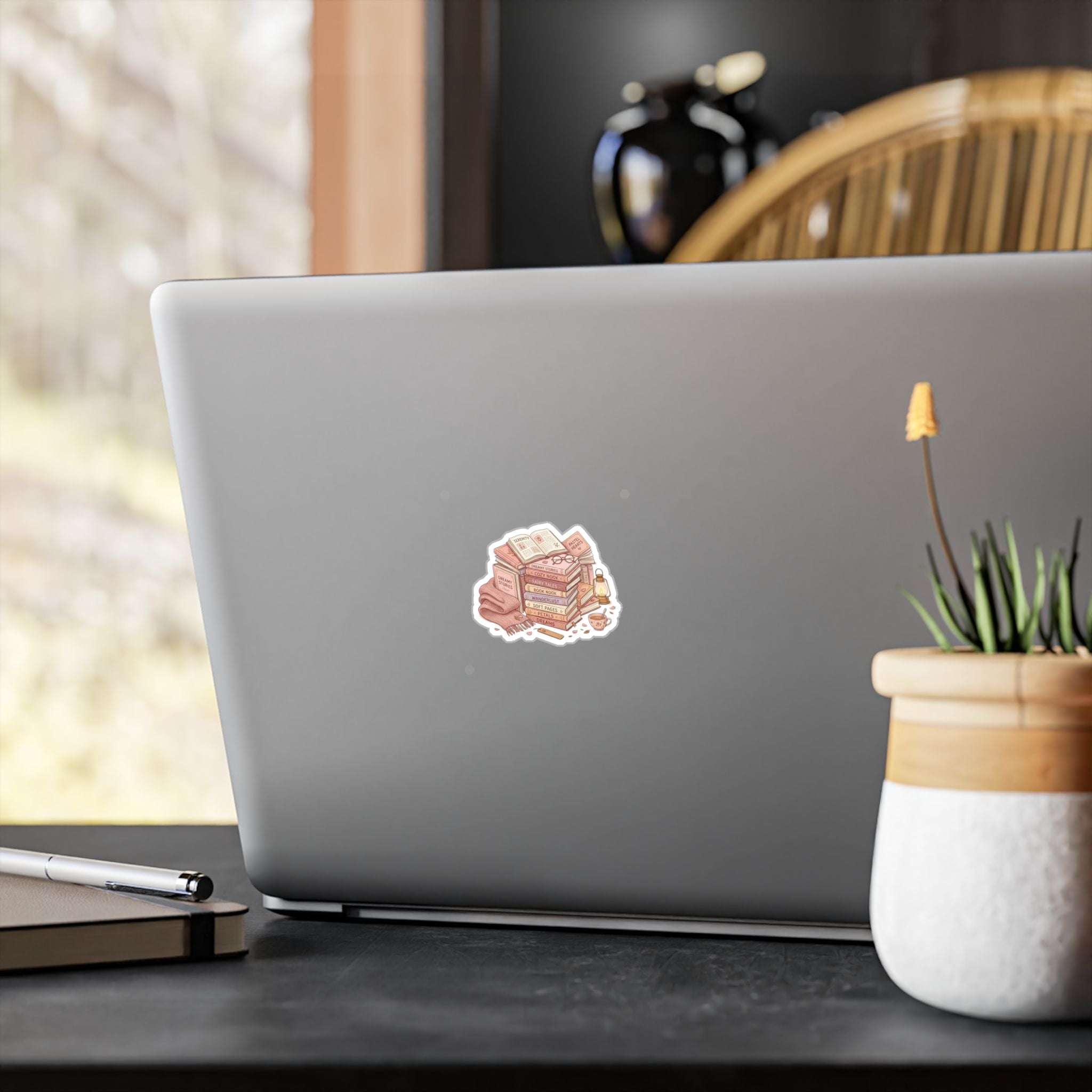 Laptop with a 'Femme Daddy' sticker on a desk with a plant and pen.