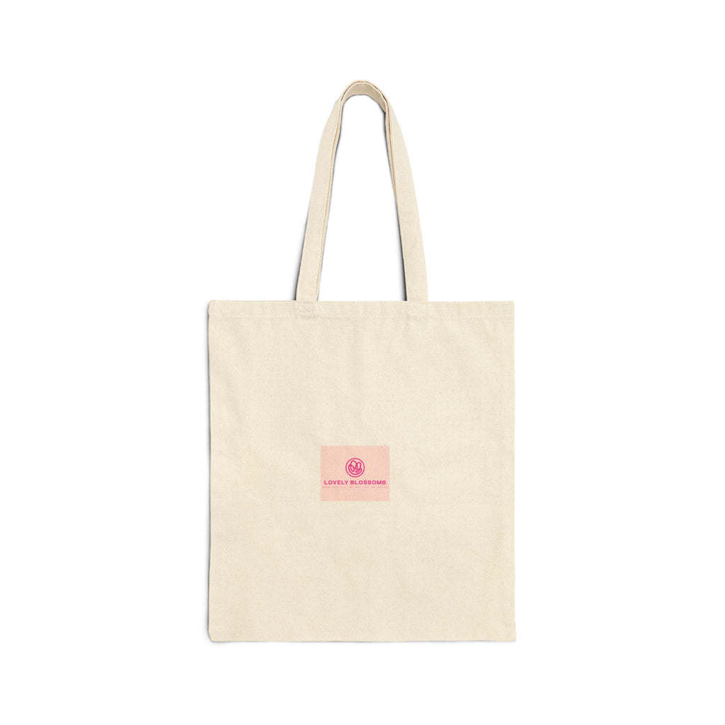 A natural beige canvas tote bag with two shoulder straps and a small pink square label on the front featuring a circular logo and the text 'Lovely Blossoms'.