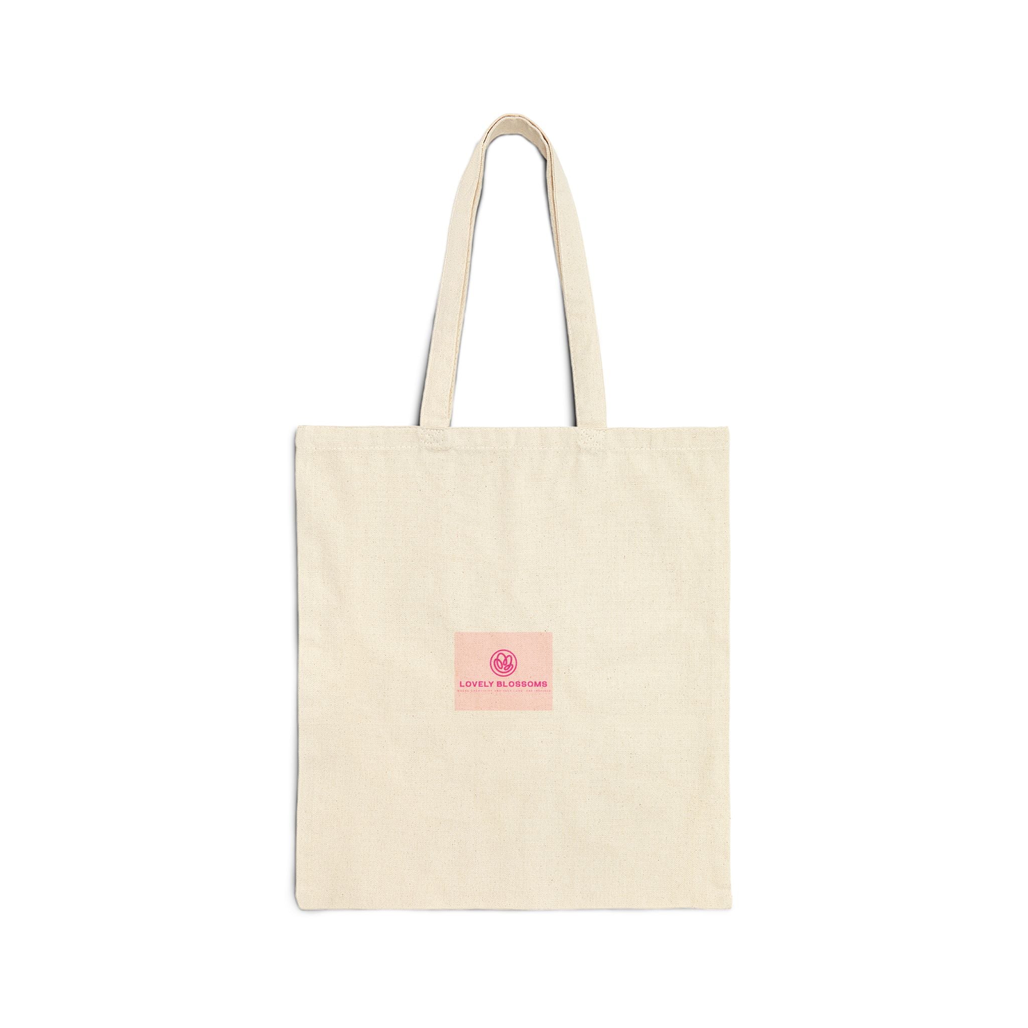A natural beige canvas tote bag with two shoulder straps and a small pink square label on the front featuring a circular logo and the text 'Lovely Blossoms'.