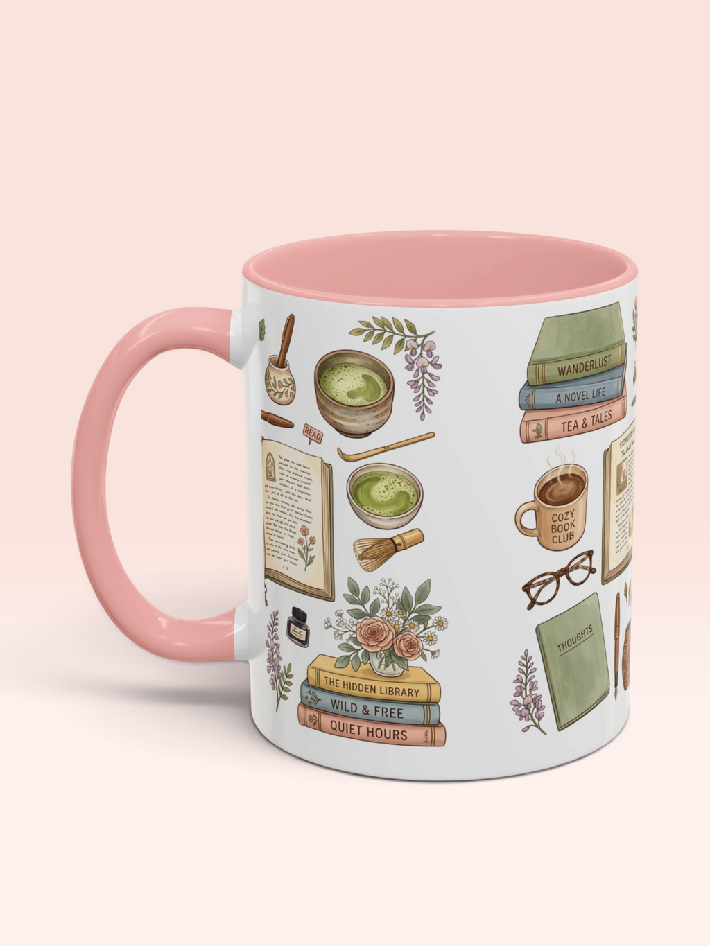 A white ceramic mug with a pink handle and interior, decorated with illustrations of cozy book-themed items like books, glasses, a bowl of green tea, and flowers, set against a soft pink background.